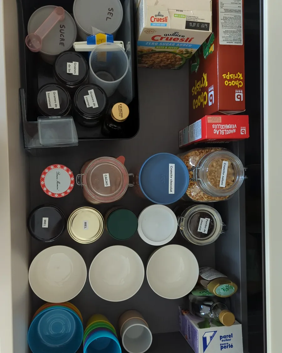 Le même tiroir après rangement par une home organiser près de Ciney : bocaux étiquetés, bols empilés, gobelets de couleur
